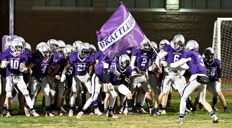Brattleboro’s Charlie Clark (3) carries the team banner as he fires up his teammates before they take the field on Oct. 21 against Mount Anthony. After several seasons of playing football in Division II, both Brattleboro and Mount Anthony will be moving up into Division I for the 2023 season.