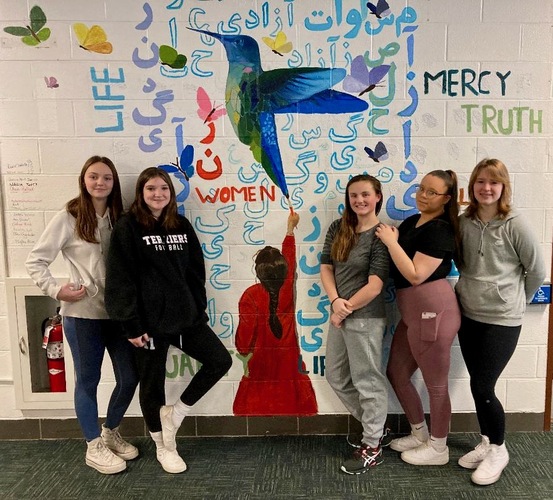 From left, ninth-graders Olivia Hallock, Aly Streeter, Jasmine Perry-Ives, Tatiana Charon, and Myleigh Illingworth stand in front of a newly created mural at Bellows Falls Union High School that celebrates freedom, justice, and creativity.