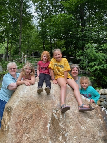 From left: former Green Mountain Camp Director Fran Lynggaard Hansen stands on the left at the stone staircase at Green Mountain Camp for Girls beside her grandchildren Ada and Geneva, followed by their friend Claire, current Director Billie Slade, and her granddaughter, Alice.