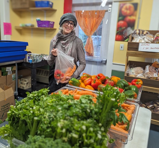 Ann Buckingham, one of 50 volunteers at the Putney Foodshelf, packs food for delivery.