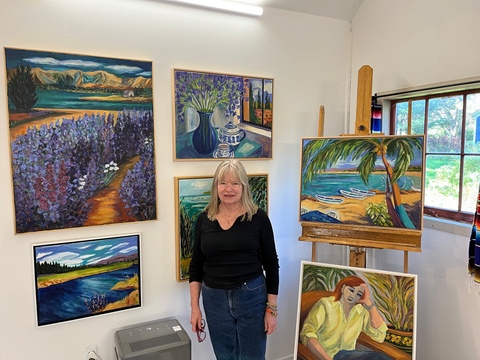 Artist Carol Keiser in her new studio with six of her many paintings.